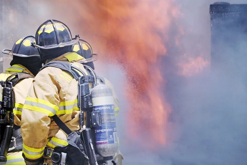 A fireman is holding two water bottles in his hands.