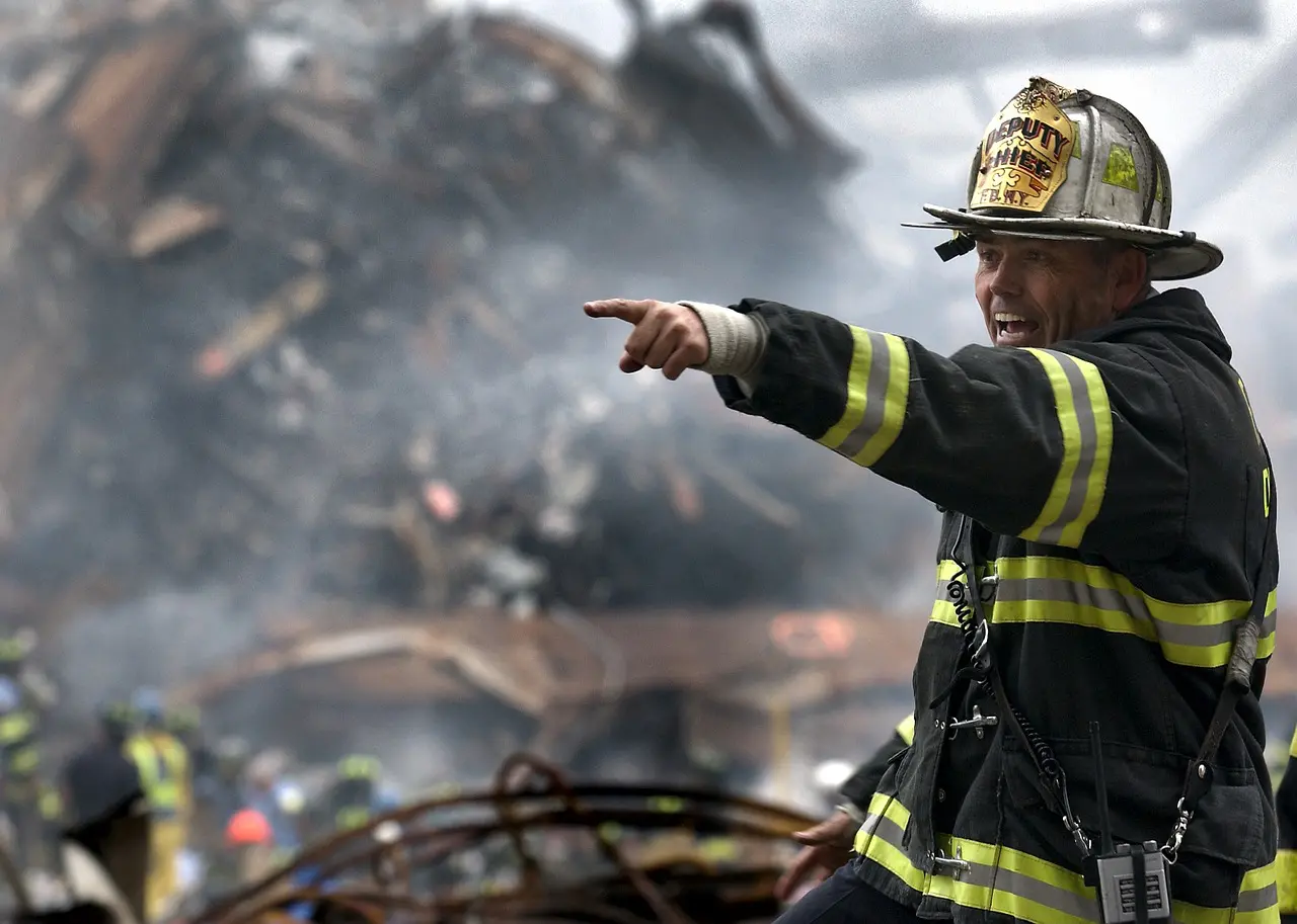 A fireman in uniform pointing to the ground.