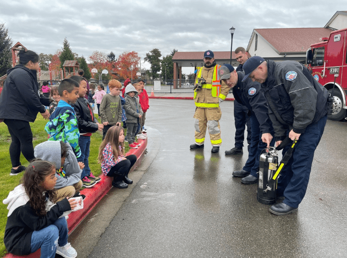 A group of people standing around with fire fighters.